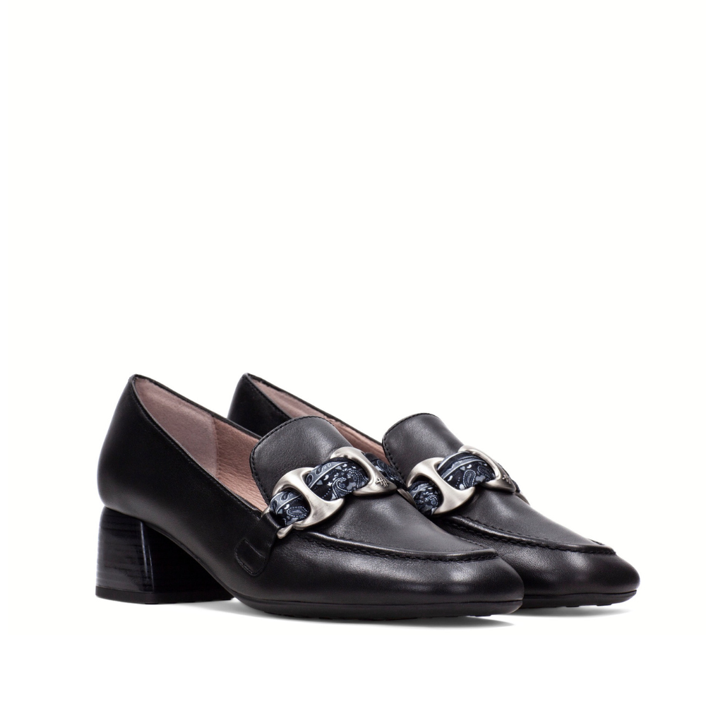 A pair of black leather block-heel loafers with a prominent silver-tone horsebit hardware detail across the vamp, shown against a plain white background.